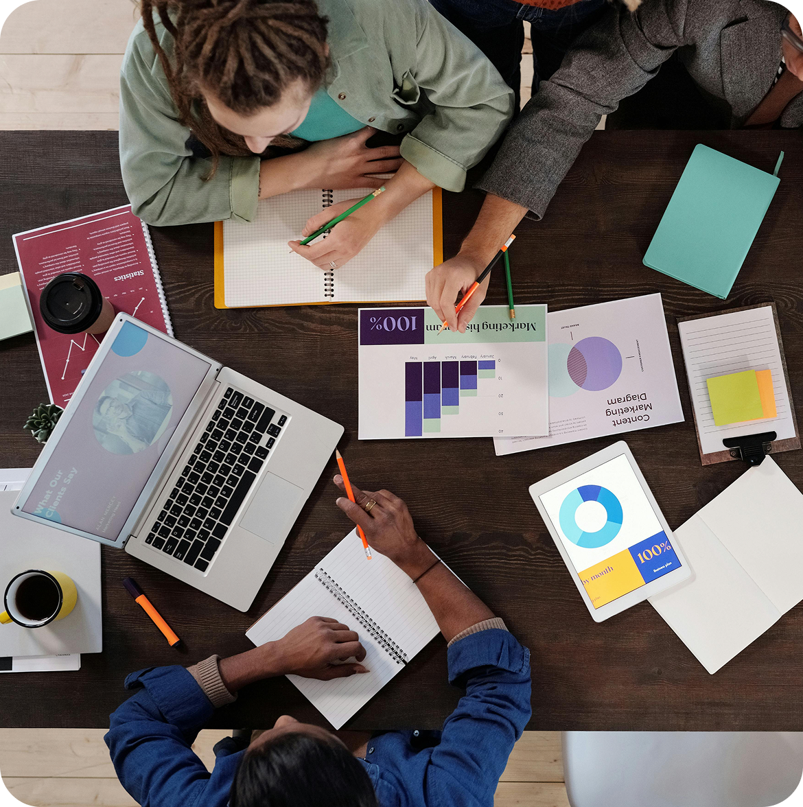 A team working together around a table with plans, notebooks and a laptop